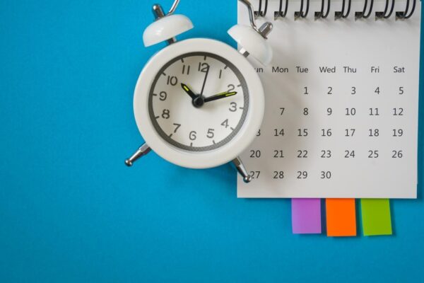 white alarm clock and calendar on blue background