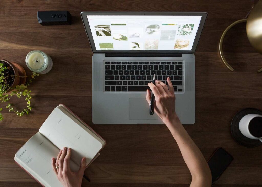 woman working on macbook and writing in diary