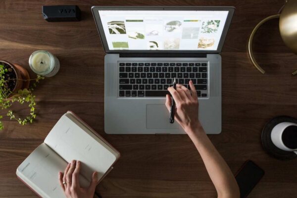 woman working on macbook and writing in diary